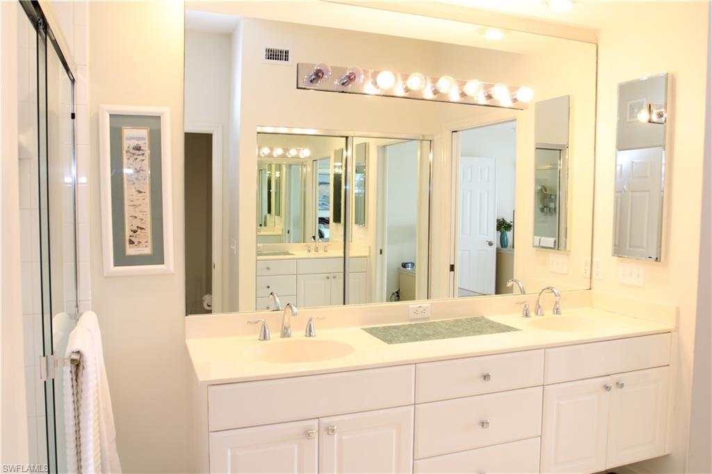 6660 Beach Resort Drive, Unit 1005 Naples, FL 34114 - Photo 30 of 38 a bathroom with a double vanity sink and a mirror