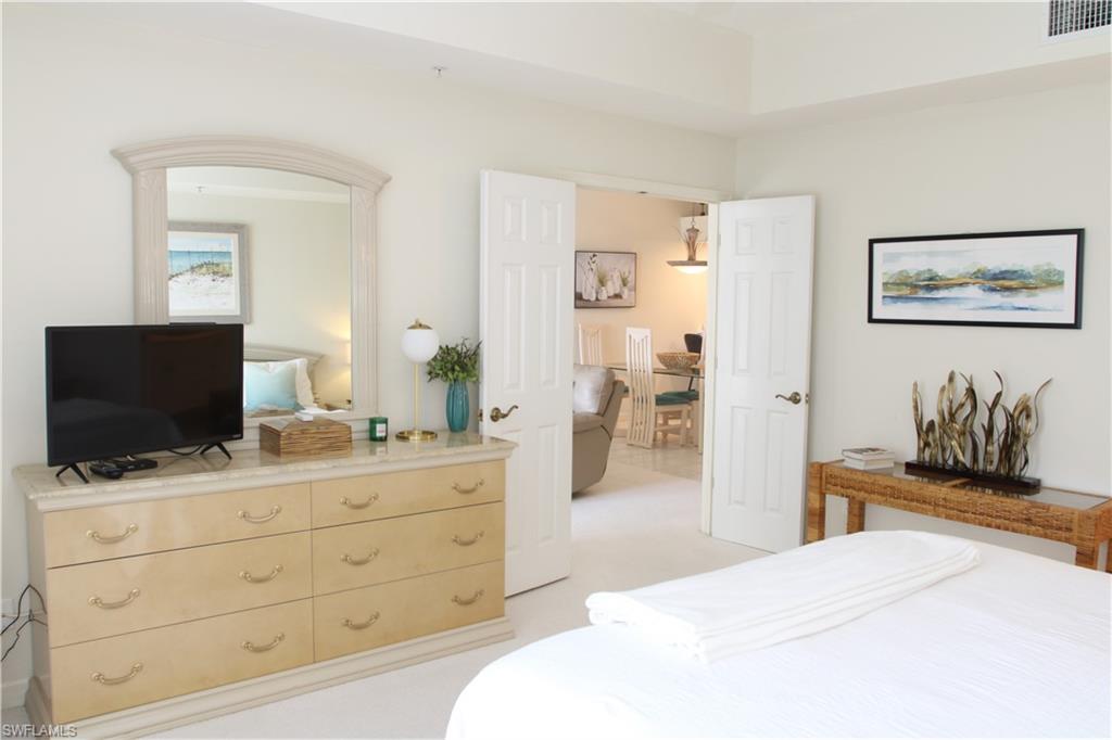 6660 Beach Resort Drive, Unit 1005 Naples, FL 34114 - Photo 3 of 38 a bedroom with a bed and a flat screen tv in it