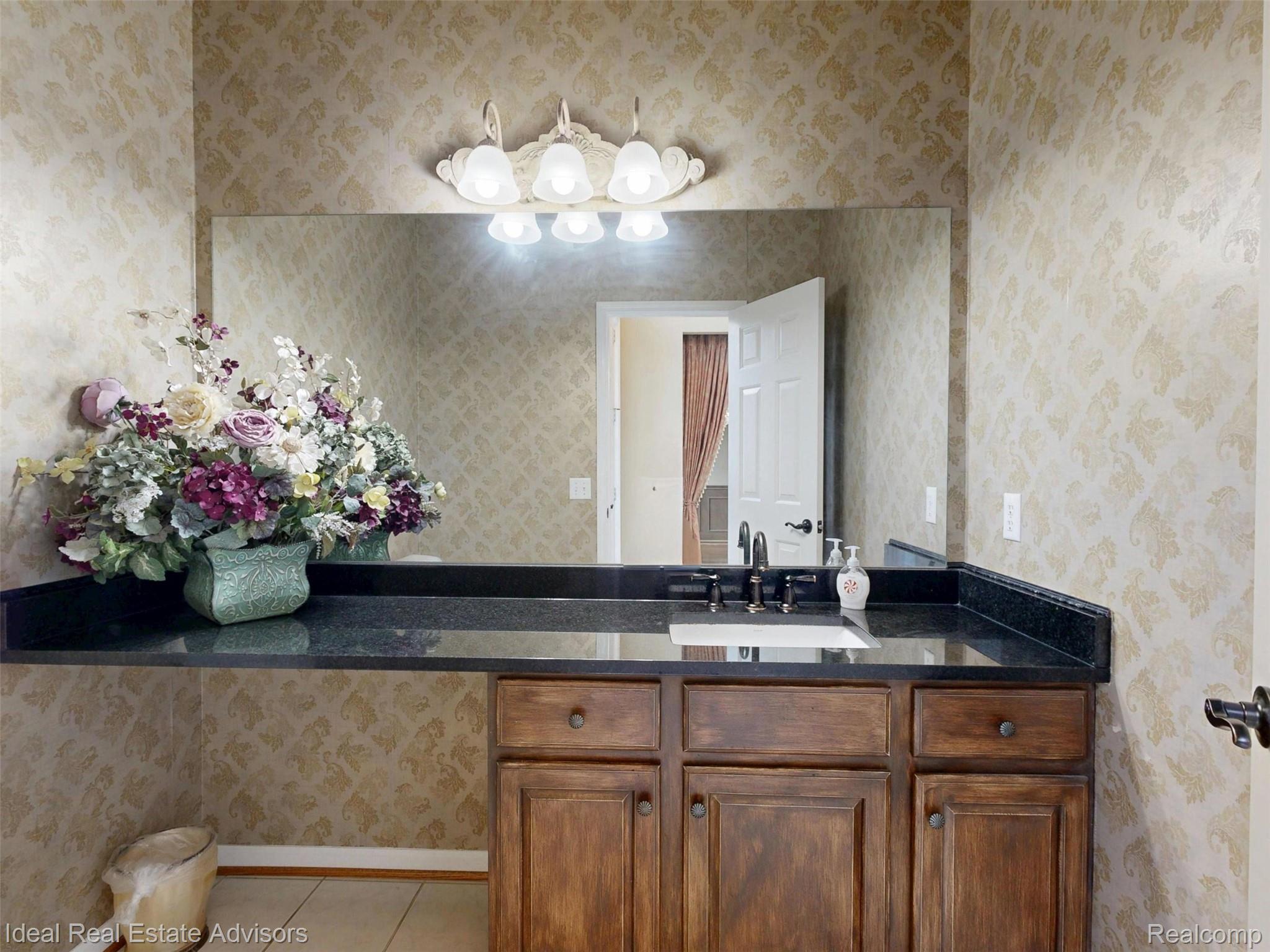 1364 Kentfield Drive Rochester, MI 48307 - Photo 40 of 70 Vanity featuring a dark stone countertop, integrated sink, and dark-finish faucet