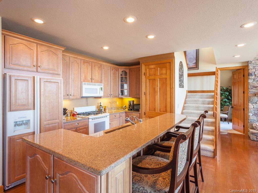 755 Andrew Banks Road Burnsville, NC 28714 - Photo 7 of 24 a kitchen with stainless steel appliances granite countertop a stove top oven a sink a dining table and chairs with wooden floor