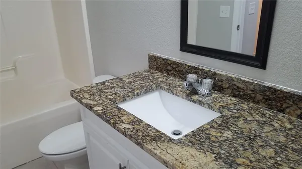 a bathroom with a granite countertop sink and a toilet