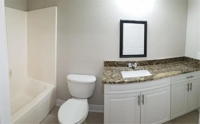 a bathroom with a granite countertop toilet sink and mirror