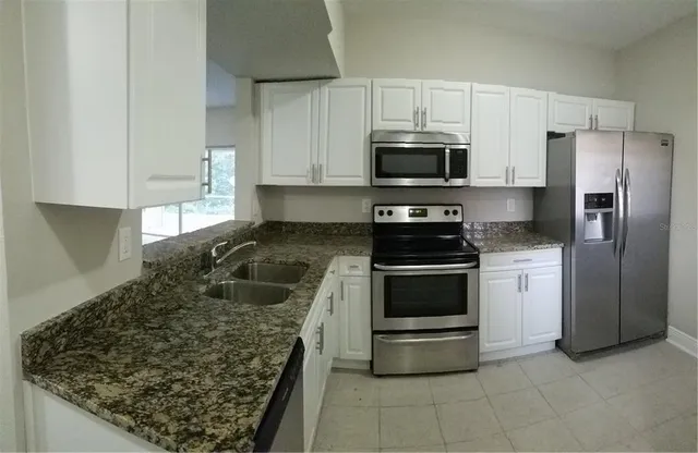 a kitchen with stainless steel appliances granite countertop a stove a refrigerator and a sink