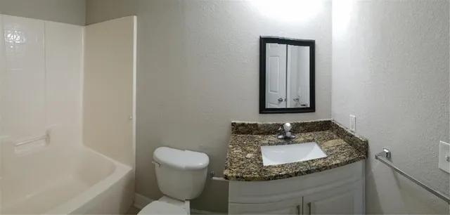 a bathroom with a granite countertop sink a mirror and a toilet