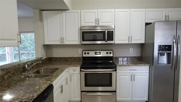 a kitchen with granite countertop a stove sink and refrigerator