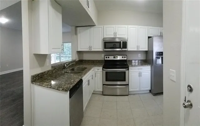 a kitchen with stainless steel appliances granite countertop a sink stove and refrigerator