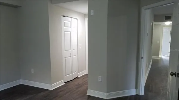 a view of an empty room with wooden floor and closet