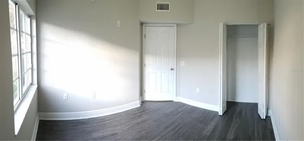 an empty room with wooden floor and windows