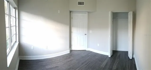 an empty room with wooden floor and windows
