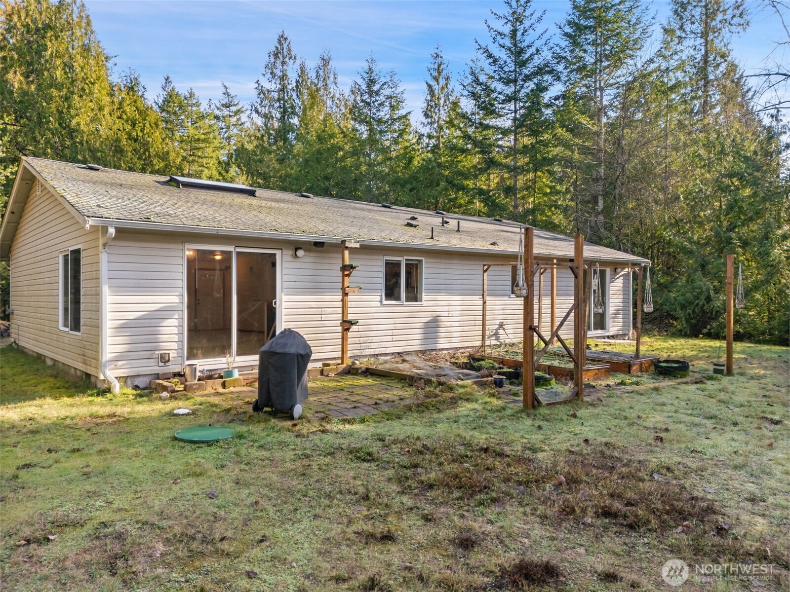 297 Lewis Road West Seabeck, WA 98380 - Photo 31 of 35 a backyard of a house with potted plants and large tree