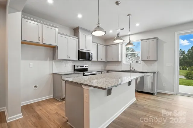 a kitchen with kitchen island granite countertop a sink a counter space appliances and cabinets