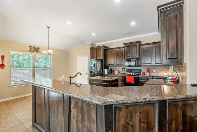 a kitchen with granite countertop a sink a stove and cabinets