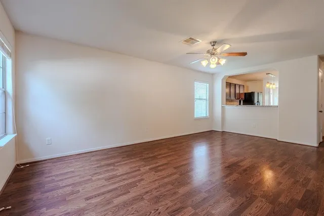 a view of an empty room with window and wooden floor