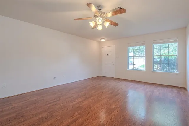 an empty room with wooden floor and windows