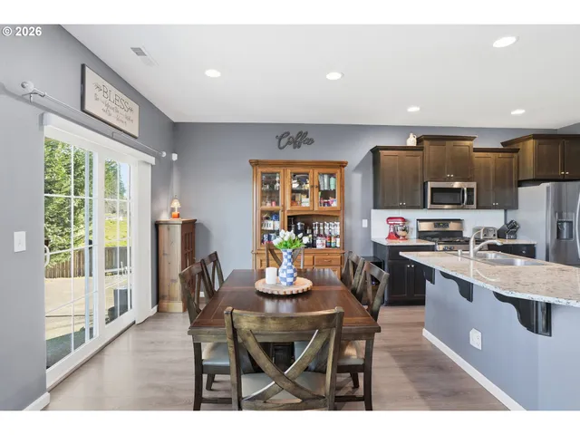 a kitchen with stainless steel appliances a dining table chairs and a refrigerator