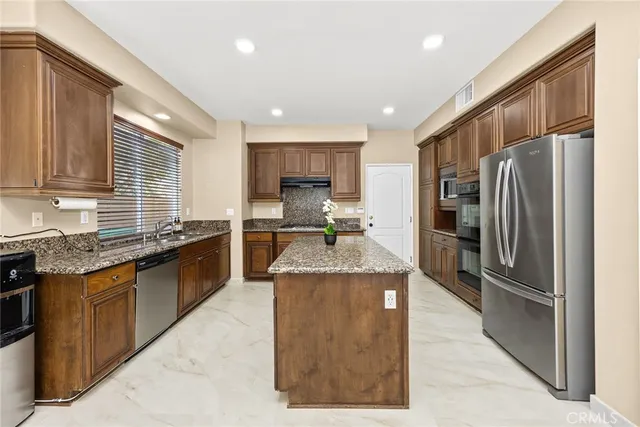 a kitchen with stainless steel appliances granite countertop a stove a sink and a refrigerator