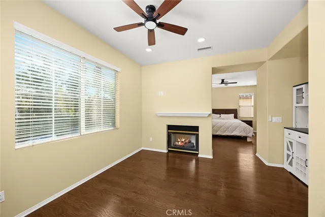 a view of a livingroom with a fireplace a ceiling fan and wooden floor