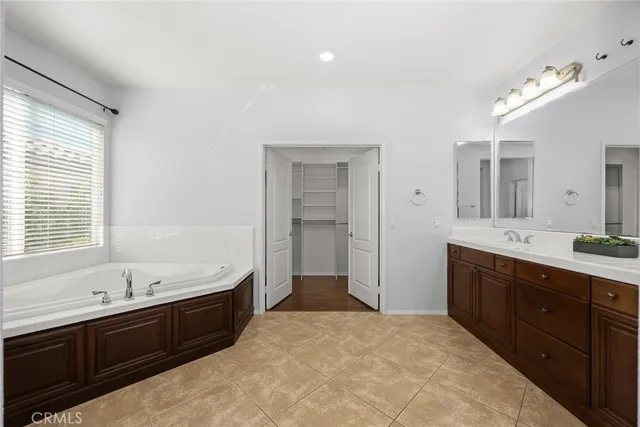 a spacious bathroom with a tub sink double vanity and mirror