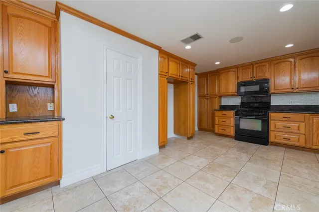 a kitchen with granite countertop wooden cabinets stainless steel appliances and a window