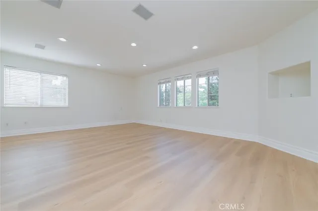 a view of empty room with window and wooden floor