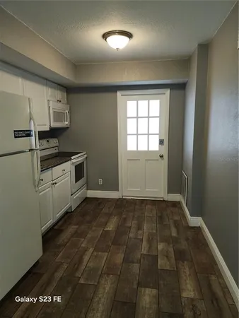 a kitchen with granite countertop a stove a sink and a refrigerator