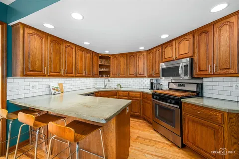 a kitchen with stainless steel appliances granite countertop wooden cabinets a stove top oven a sink and dishwasher with wooden floor