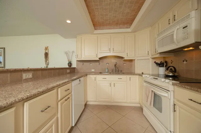 a kitchen with granite countertop white cabinets and white appliances