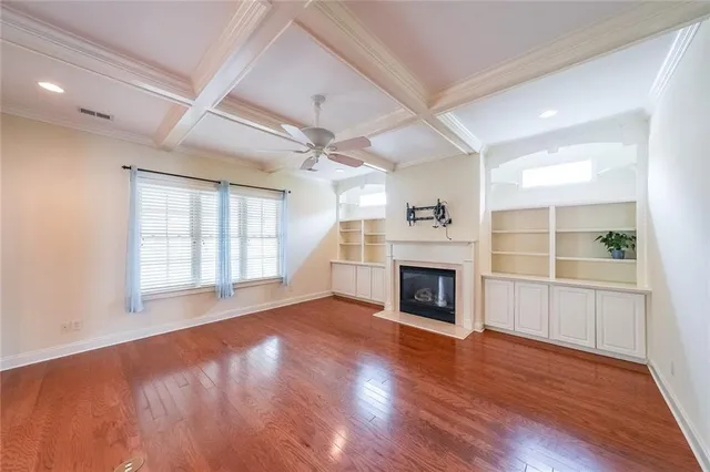 an empty room with wooden floor fireplace and windows
