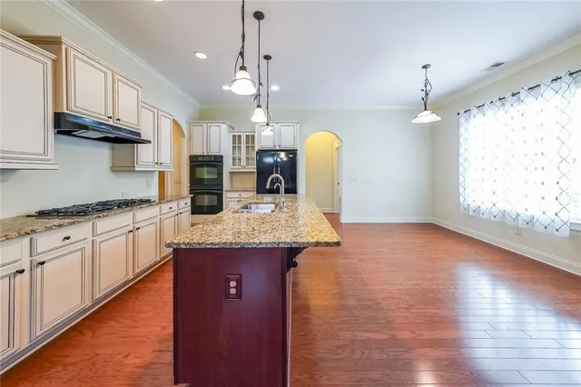 a kitchen with stainless steel appliances granite countertop a sink a stove top oven a counter space and wooden floor