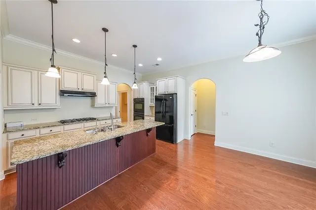 a large kitchen with stainless steel appliances granite countertop a stove a refrigerator and a wooden floors