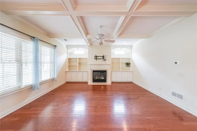 an empty room with wooden floor fireplace and windows