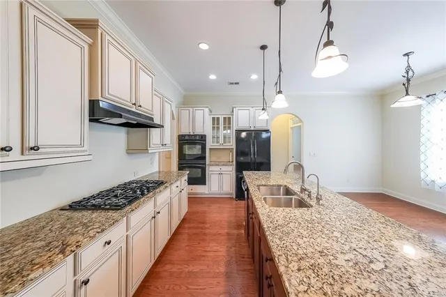 a kitchen with granite countertop a stove a sink and a refrigerator
