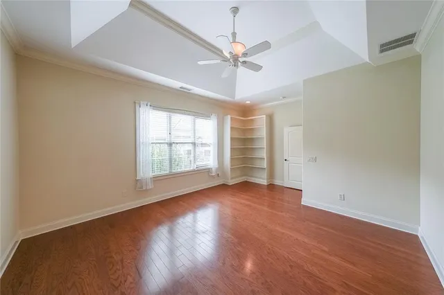 an empty room with wooden floor fan and windows