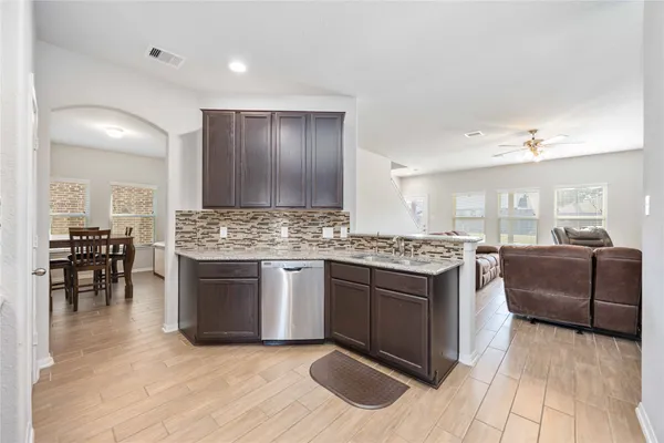 a kitchen with stainless steel appliances granite countertop a stove top oven a sink dishwasher and white cabinets with wooden floor