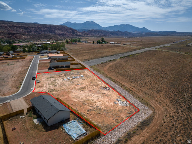 212 Lidia Circle, Unit 17 Moab, UT 84532 - Photo 2 of 24 Expansive undeveloped land parcel outlined in red, featuring a partial paved road frontage and surrounding natural terrain