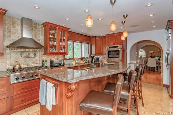 a kitchen with stainless steel appliances granite countertop a sink a stove and a wooden cabinets