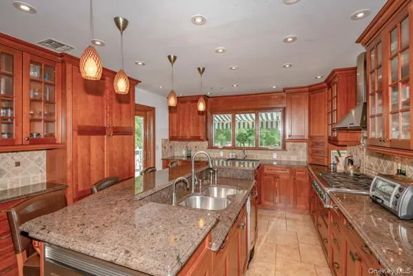 a kitchen with stainless steel appliances granite countertop a sink a stove and a wooden cabinets
