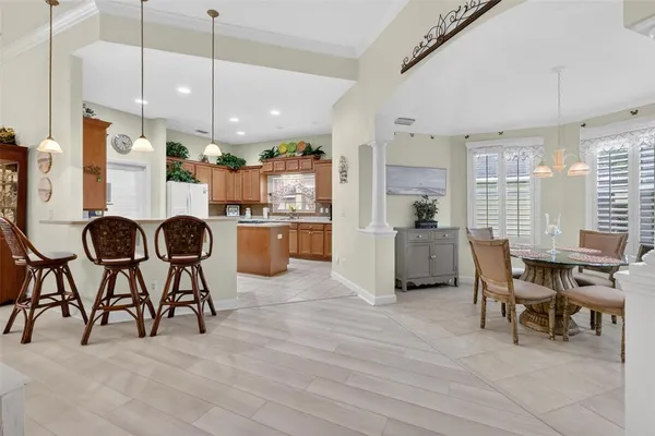 a open kitchen with stainless steel appliances granite countertop a stove top oven a refrigerator a dining table chairs with white cabinets and wooden floor