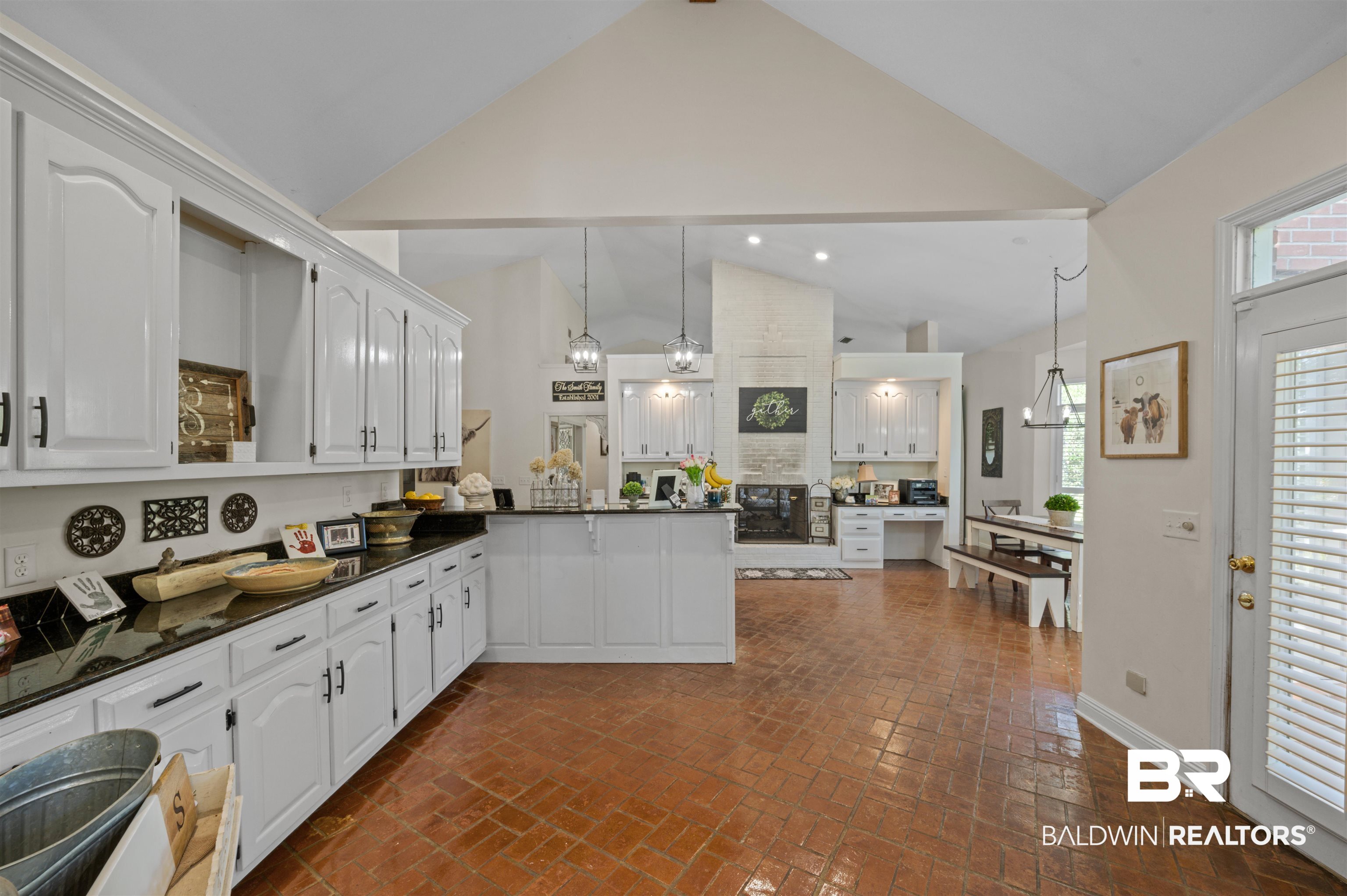 141 Blue Ridge Drive Monroeville, AL 36460 - Photo 15 of 40 Kitchen with high vaulted ceiling, white cabinets, a peninsula, and brick floors