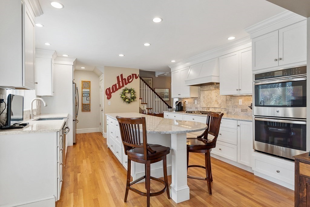 212 Hawthorne Lane Concord, MA 01742 - Photo 12 of 41 a kitchen with granite countertop kitchen island stainless steel appliances a stove a sink a refrigerator with a dining table and chairs