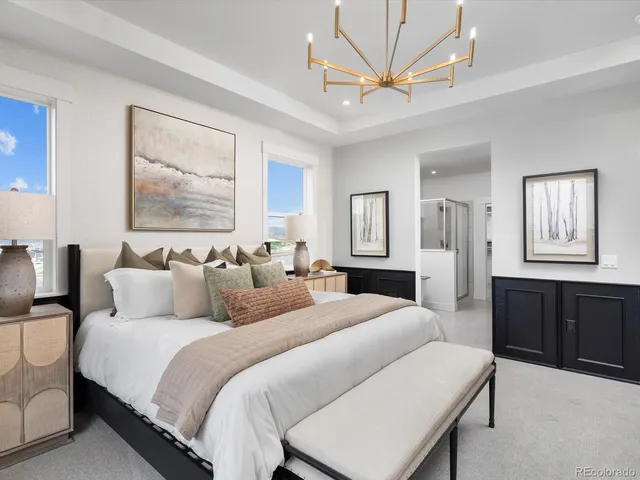 a spacious bedroom with a bed a dresser and a chandelier