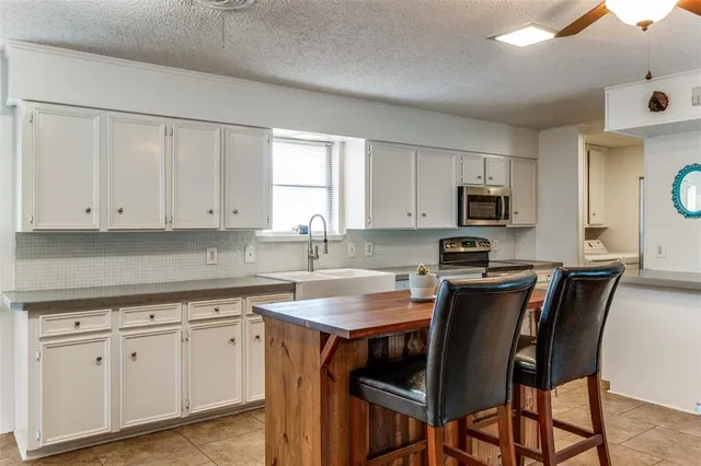 a large white kitchen with a window and stainless steel appliances
