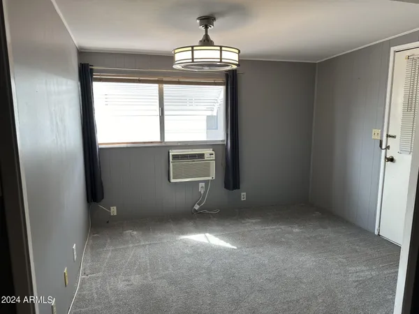 an empty room with chandelier fan and windows