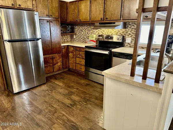a kitchen with stainless steel appliances granite countertop a refrigerator a stove and a refrigerator with wooden floor