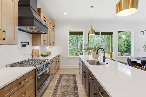 a kitchen with stainless steel appliances granite countertop a sink a stove and a wooden floors