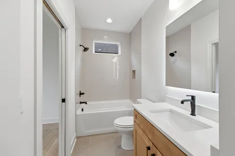 a bathroom with a toilet a sink a mirror a bathtub and vanity