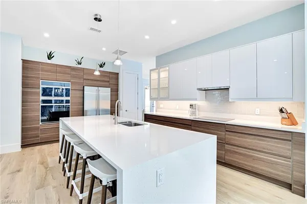 a kitchen with stainless steel appliances granite countertop a sink a stove a refrigerator and white cabinets with wooden floor