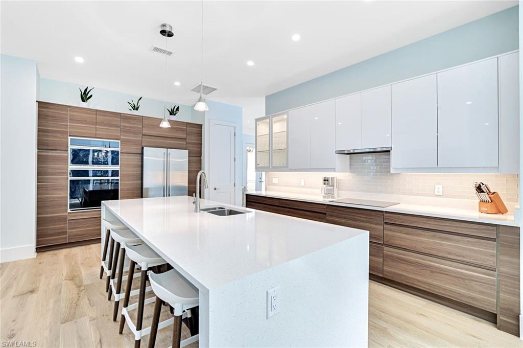 2515 Royal Palm Court Naples, FL 34103 - Photo 11 of 32 a kitchen with stainless steel appliances granite countertop a sink a stove a refrigerator and white cabinets with wooden floor