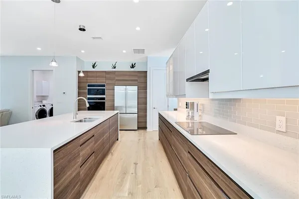 a large kitchen with a large counter top a sink stainless steel appliances and cabinets