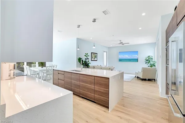 a large white kitchen with a stove a sink dishwasher and a refrigerator with wooden floor